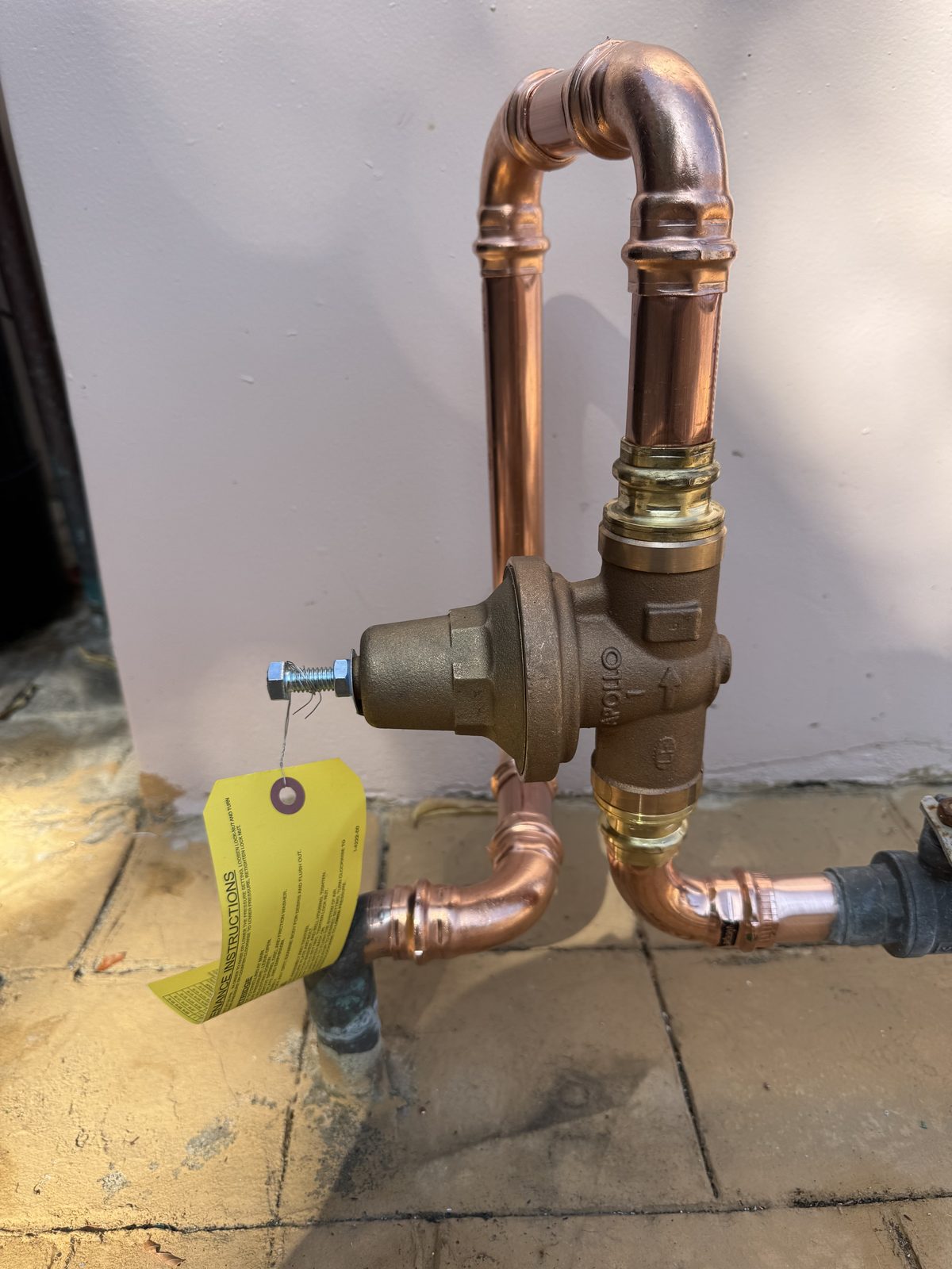 After: new brass pressure reducing valve on clean copper piping, lowering water pressure to protect the water heater and plumbing